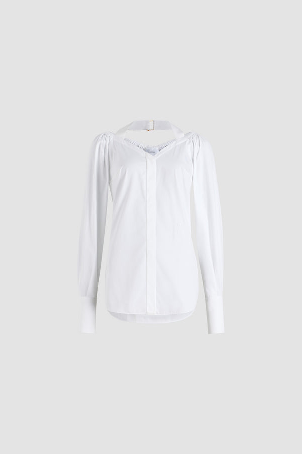 Patou - オーガニック コットンポプリン ラップブラウス - White - ホワイトのオーガニックコットンポプリン製ブラウス。バスト周りに巻きつけて背面で結ぶ、取り外し可能なトップレイヤーデザイン。伸縮性のあるショルダーとグログランホルターネックストラップを配したワイドなネックライン。隠しボタン留め。袖口にボタン付きの長めのスリーブ。前面にJPモノグラム刺繍。
