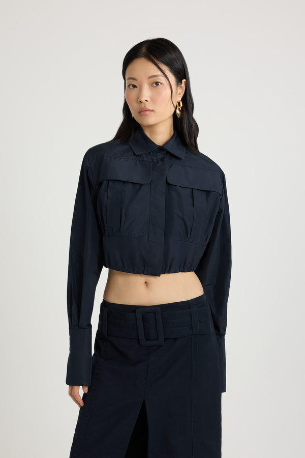 Patou - Cropped safari shirt in recycled faille - Navy Black - Navy Black recycled polyester faille shirt. Cropped length. Shirt collar. Concealed button front fastening. High chest flap pockets. Elongated sleeves with buttoned cuffs. Inverted back pleat. Drawstring hem with tie fastening at the back.