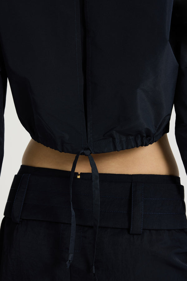 Patou - Cropped safari shirt in recycled faille - Navy Black - Navy Black recycled polyester faille shirt. Cropped length. Shirt collar. Concealed button front fastening. High chest flap pockets. Elongated sleeves with buttoned cuffs. Inverted back pleat. Drawstring hem with tie fastening at the back.