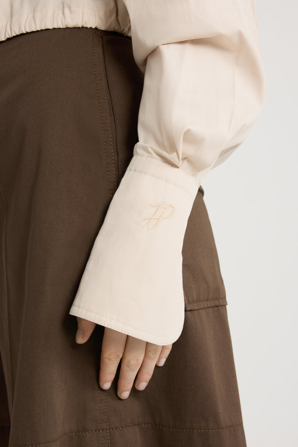 Patou - Camicia safari corta in popeline di cotone bio - Tapioca - Camicia in popeline di cotone bio beige tapioca. Modello corto. Colletto classico. Abbottonatura nascosta. Tasche a toppa alte sul petto. Maniche allungate con polsini abbottonati. Monogramma JP ricamato sulla manica sinistra. Piega sul retro. Vita con coulisse con allacciatura sul retro.