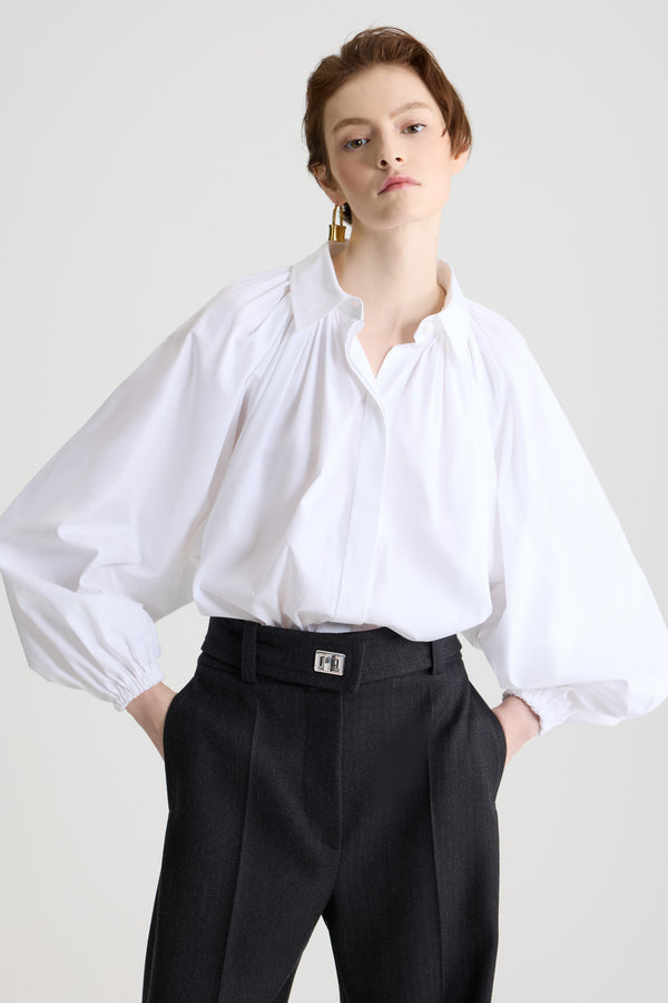 Patou - Blouse bouffante en popeline de coton bio - White - Blouse en coton bio blanc. Silhouette volumineuse. Modèle légèrement court. Col chemise classique. Fermeture par bouton dissimulé à l’avant. Manches ballon avec poignets élastiques. Ourlet bouffant.