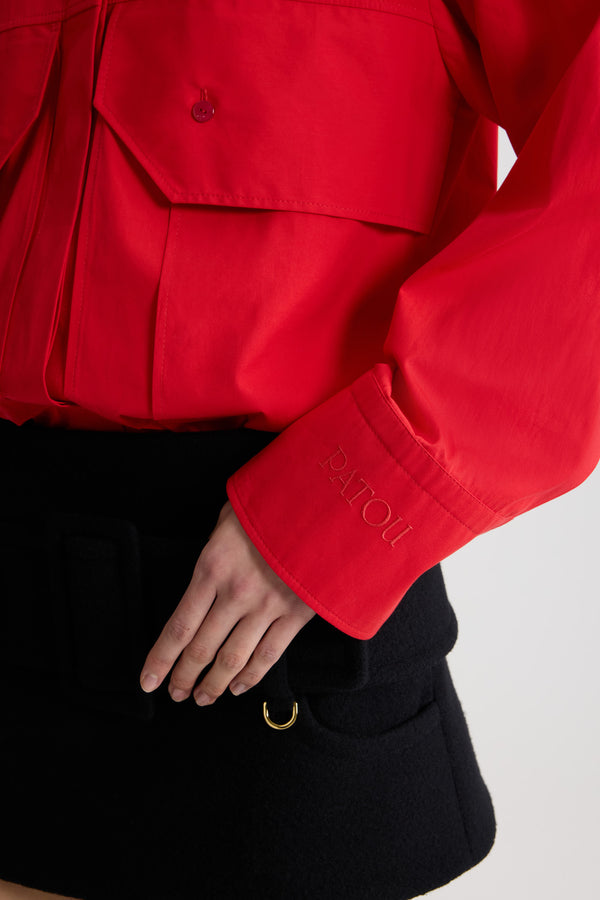 Patou - Blouse cargo en popeline de coton bio - Elixir Red - Blouse en popeline de coton bio rouge élixir. Silhouette droite. Col chemise classique. Fermeture par bouton dissimulé à l’avant. Poches à rabat larges sur la poitrine. Poignets boutonnés avec logo Patou brodé sur la manche gauche.