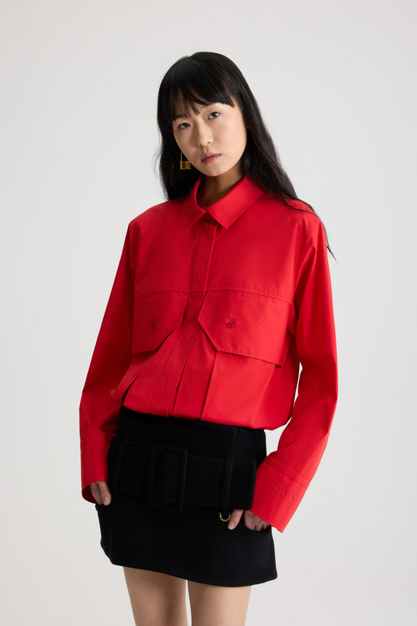 Patou - Blouse cargo en popeline de coton bio - Elixir Red - Blouse en popeline de coton bio rouge élixir. Silhouette droite. Col chemise classique. Fermeture par bouton dissimulé à l’avant. Poches à rabat larges sur la poitrine. Poignets boutonnés avec logo Patou brodé sur la manche gauche.