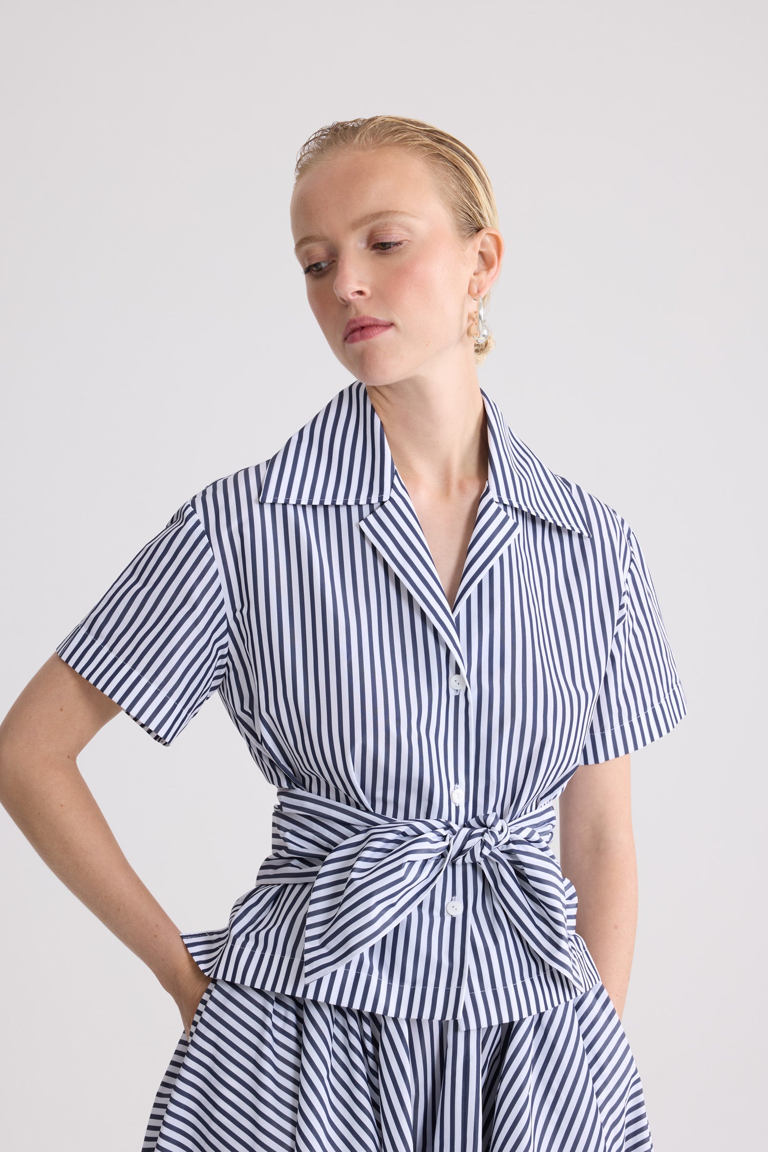Patou - Chemise nouée en faille recyclée - Offshore Stripes - Chemise nouée à rayures bleues et blanches. Manches courtes. Col chemise. Détail noué à la taille.