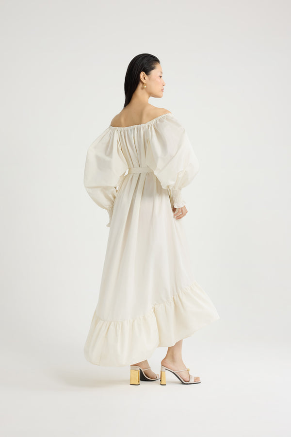 Patou - Robe cocktail longue en faille recyclée - Ivory - Robe en faille recyclée ivoire. Modèle long. Construction à volants. Silhouette asymétrique plus longue au dos. Encolure élastiquée pouvant dévoiler les épaules. Manches volumineuses à poignets smockés. Ceinture à la taille. Poches latérales.Cette robe fait partie de la collection Cérémonie créée pour les occasions spéciales.