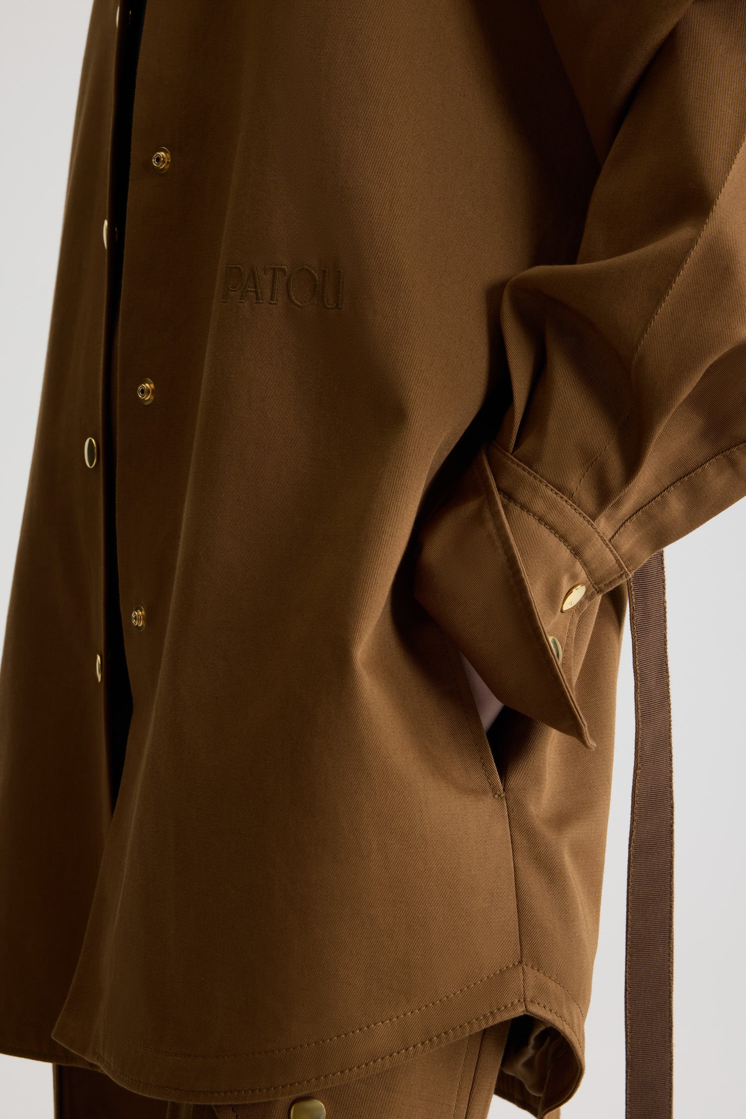 Patou - オーガニックコットンギャバジン ミニシャツドレス - Nutmeg - ナツメグライトブラウンのオーガニックコットンギャバジン製ドレス。ショート丈。ストレートシルエット。シャツカラー。ゴールドトーンのJP刻印入りボタン。ショルダータブ。ボリューム感のあるラグランスリーブ。袖口にボタン付き。ウエストに取り外し可能なセルフタイベルト前面にパトゥの刺しゅうロゴとJPモノグラム。