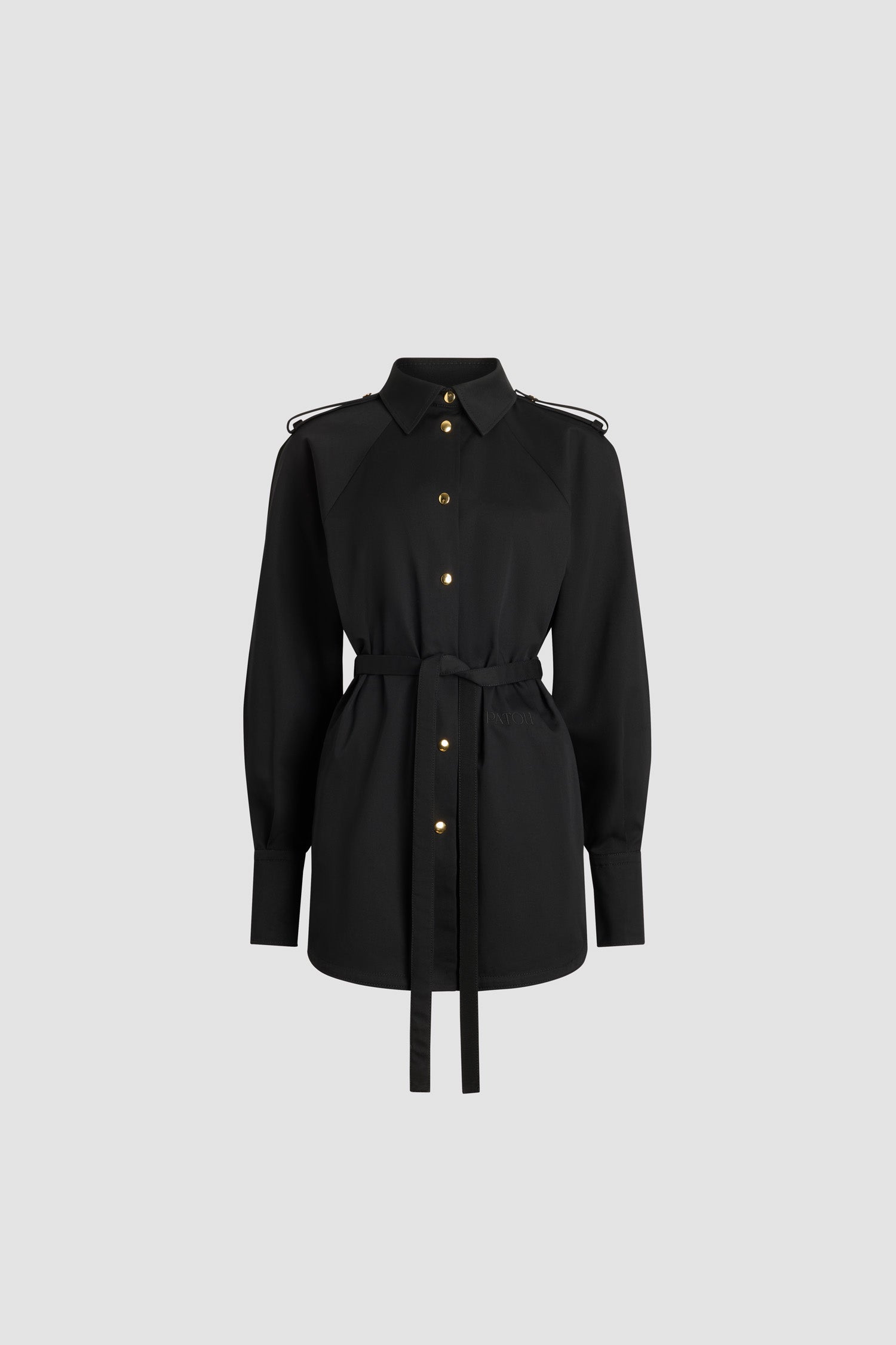 Patou - Robe chemise courte en gabardine de coton bio - Black - Robe en gabardine de coton bio noire. Modèle court. Silhouette droite. Col chemise. Boutons dorés gravés du monogramme JP. Pattes d’épaule. Manches raglan volumineuses. Poignets boutonnés. Ceinture amovible à la taille. Logo Patou et monogramme JP brodés sur le devant.