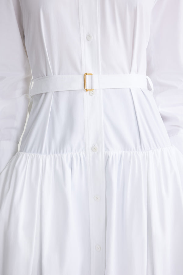 Patou - Robe chemise longue en coton bio - White - Robe en popeline de coton bio blanche. Modèle long. Jupe volumineuse à étages. Col de chemise. Boutons en nacre gravés JP. Pattes d&#39;épaules. Manches raglan. Poignets boutonnés. Ceinture amovible à la taille avec boucle dorée.
