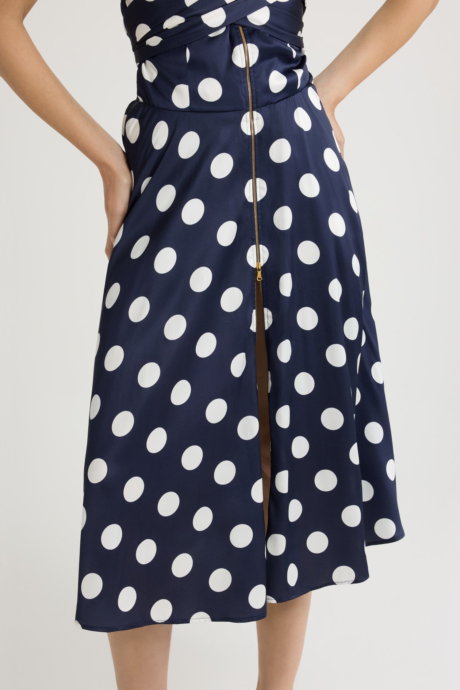 Patou - Robe midi en satin imprimé - Navy Polka Dots - Robe en satin bleu marine. Imprimé pois. Longueur midi. Bretelle tour-de-cou en gros-grain. Bustier croisé drapé à nouer au dos. Fermeture par zip doré sur le devant. Dos élastiqué.