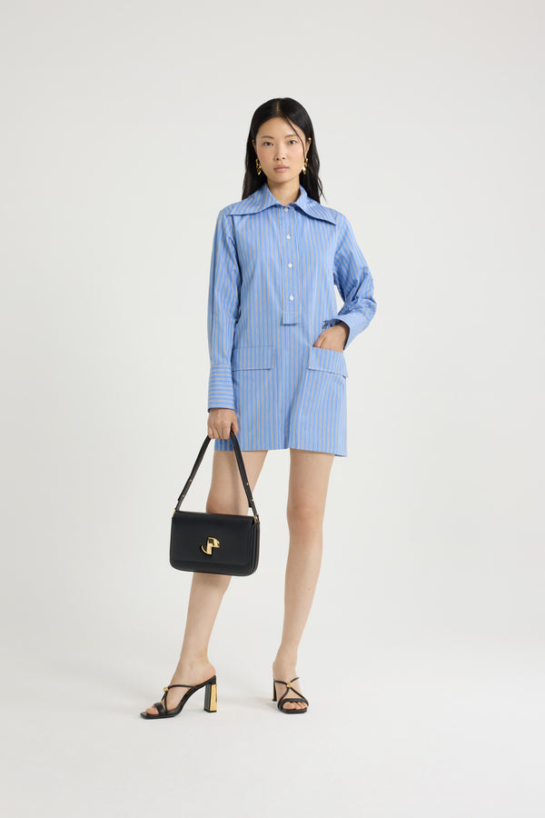 Patou - Robe courte en popeline de coton bio imprimée - Heritage Blue Stripes - Robe en popeline de coton bio bleu héritage. Imprimé rayures. Modèle court. Coupe droite. Col ample. Boutonnage partiel sur le devant. Monogramme JP calligraphie brodé sur le devant. Poches à rabat. Poignets boutonnés.