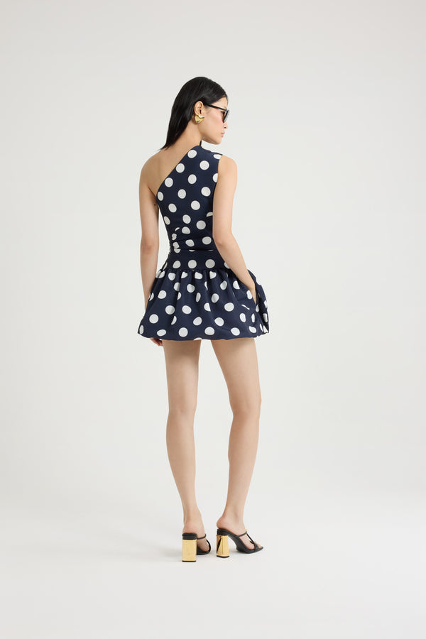 Patou - Vestito mini monospalla in ottomano stampato riciclato - Navy Polka Dots - Vestito in ottomano riciclato blu scuro. Fantasia pois. Lunghezza mini. Silhouette monospalla asimmetrica. Bustino drappeggiato. Chiusura con zip al lato. Gonna a palloncino.