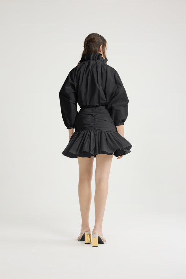 Patou - Robe courte à manches bouffantes en faille recyclée - Black - Robe en faille recyclée noire. Modèle court. Haut volumineux et bas ajusté. Col à coulisse avec détail de fronce et gros-grain. Manches chauve-souris resserrées aux poignets. Jupe froncée avec volant au bas. Fermeture par zip sur le côté.Cette robe fait partie de la collection Cérémonie créée pour les occasions spéciales.