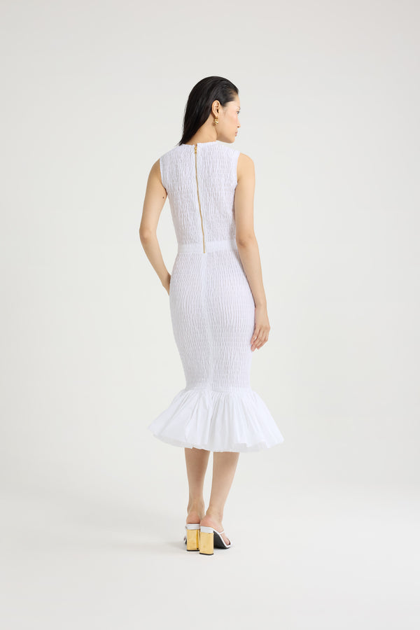 Patou - Robe midi smockée à ourlet volanté en faille recyclé - White - Robe en faille recyclée blanche. Longueur midi. Silhouette ajustée. Modèle sans manches. Zip doré au dos. Taille élastiquée. Ourlet volanté. Cette robe fait partie de la collection Cérémonie créée pour les occasions spéciales.