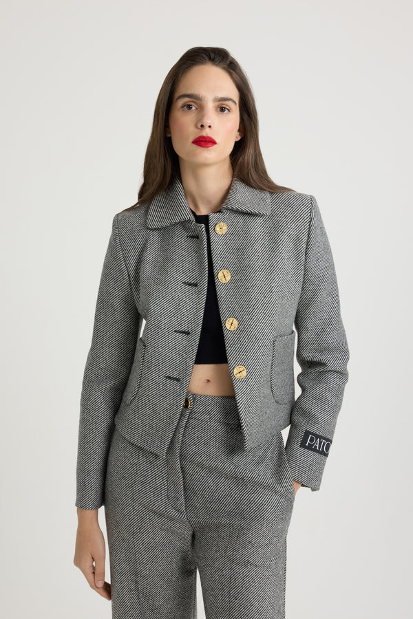 Patou - 텍스처드 울 소재의 쇼트 재킷 - Graphite - 24시간 언제라도 완벽한 테일러드 및 에포트리스 디자인의 재킷.그래파이트 그레이 울 재킷. 대각선으로 이어진 투톤 스트라이프 디테일의 텍스처드 테일러링 패브릭. 크롭 기장 실루엣. 와이드 칼라. 아르데코 스타일의 골드 톤 JP 인그레이빙 버튼. 앞면의 패치 포켓. 컨실 버튼 커프스. 파투 라벨이 장식된 슬리브. 뒷면의 싱글 벤트. 전체 안감 처리.허리의 타이트한 핏.