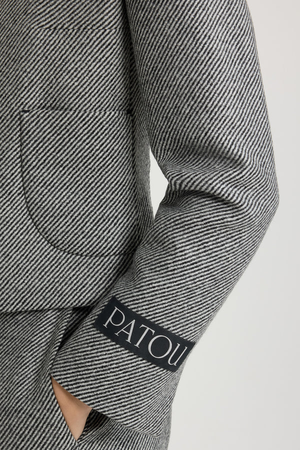 Patou - 텍스처드 울 소재의 쇼트 재킷 - Graphite - 24시간 언제라도 완벽한 테일러드 및 에포트리스 디자인의 재킷.그래파이트 그레이 울 재킷. 대각선으로 이어진 투톤 스트라이프 디테일의 텍스처드 테일러링 패브릭. 크롭 기장 실루엣. 와이드 칼라. 아르데코 스타일의 골드 톤 JP 인그레이빙 버튼. 앞면의 패치 포켓. 컨실 버튼 커프스. 파투 라벨이 장식된 슬리브. 뒷면의 싱글 벤트. 전체 안감 처리.허리의 타이트한 핏.