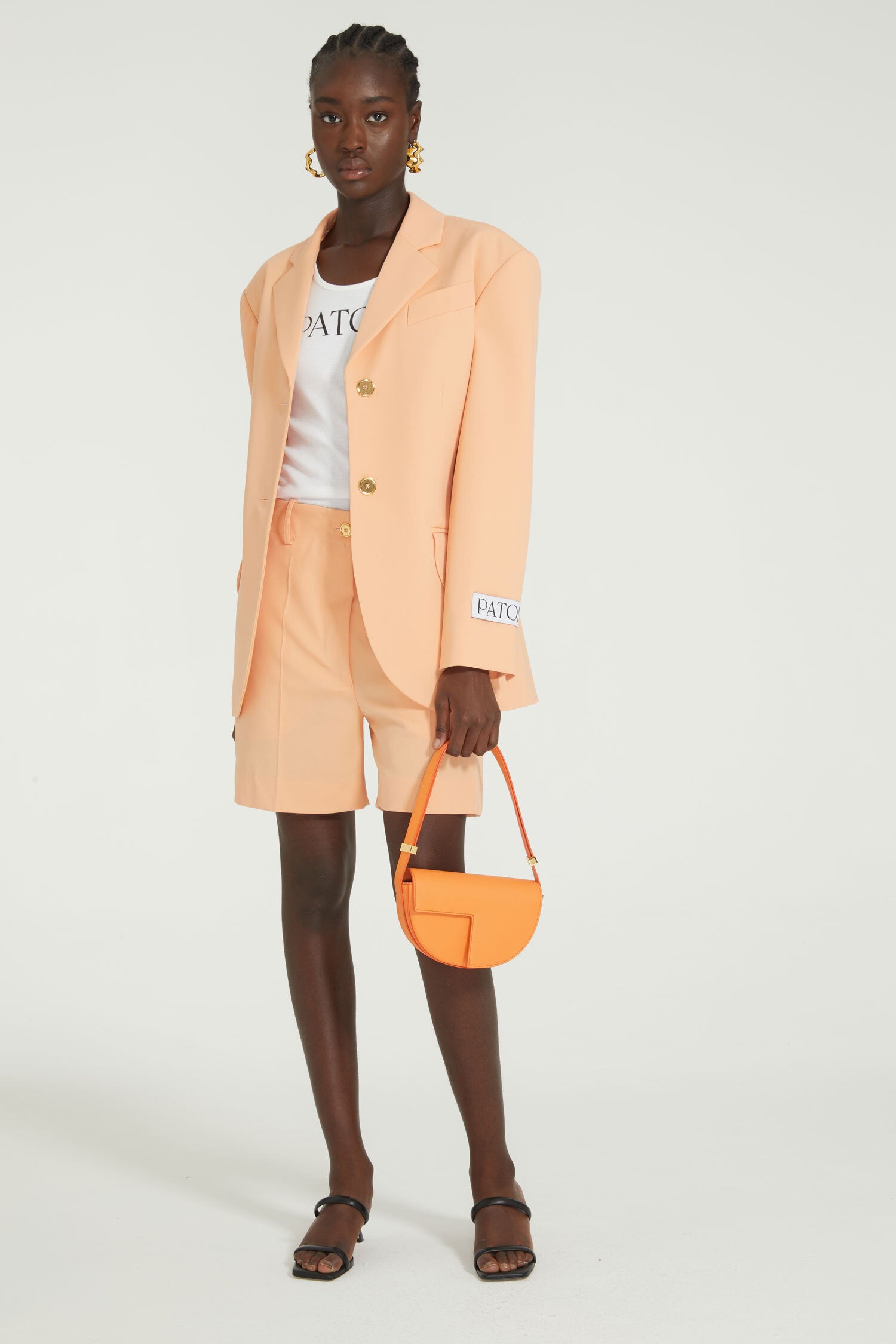 Patou - Belted tailored jacket in technical wool - Light orange - One perfect tailored jacket, endless possibilities.Light orange technical wool twill jacket. Double-breasted style. Fitted tailored silhouette. Wide notch lapels. Two gold-tone Patou-engraved buttons. Fabric belt at the waist. Flap pockets. Cropped sleeves. Patou label on the left sleeve.