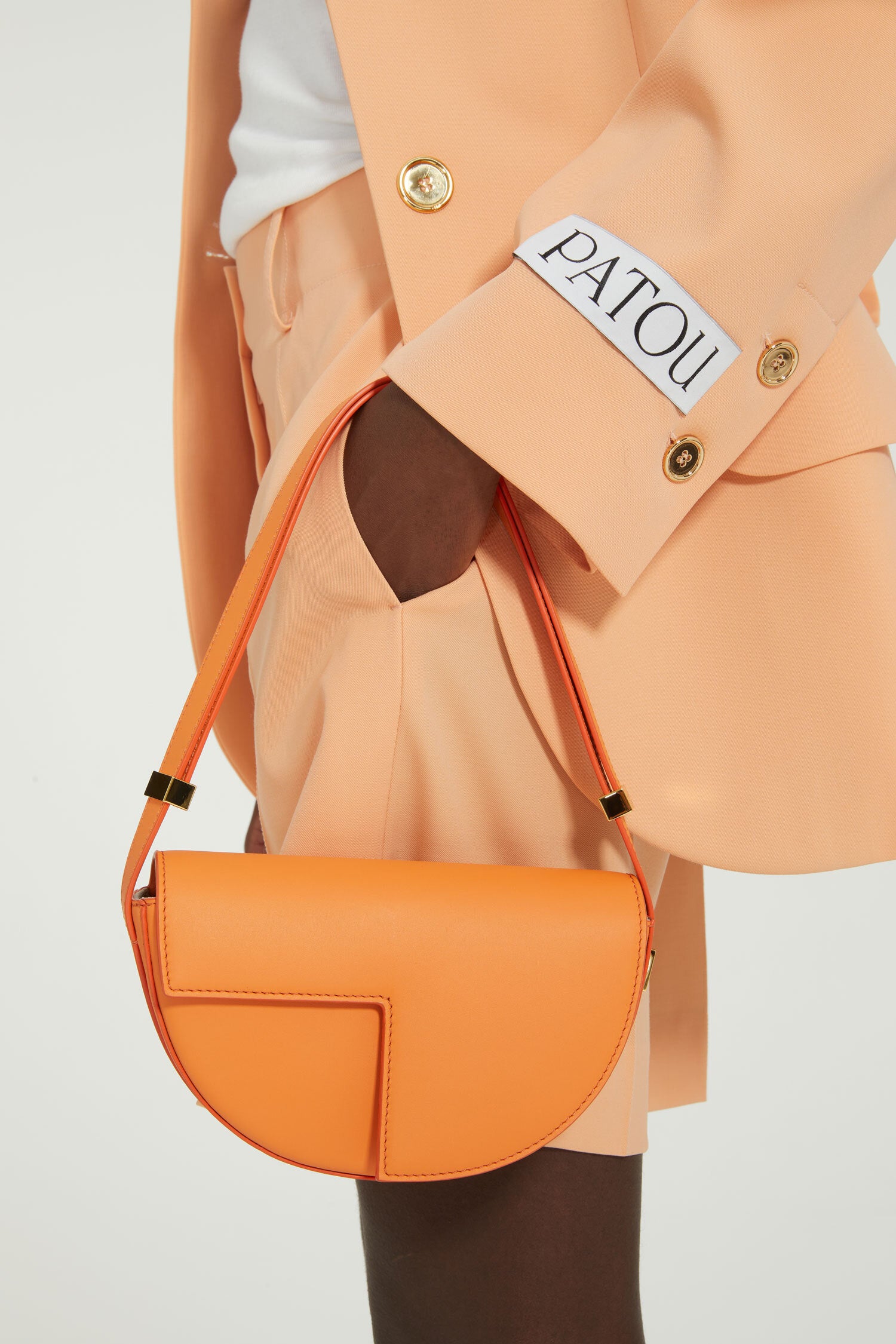 Patou - Belted tailored jacket in technical wool - Light orange - One perfect tailored jacket, endless possibilities.Light orange technical wool twill jacket. Double-breasted style. Fitted tailored silhouette. Wide notch lapels. Two gold-tone Patou-engraved buttons. Fabric belt at the waist. Flap pockets. Cropped sleeves. Patou label on the left sleeve.