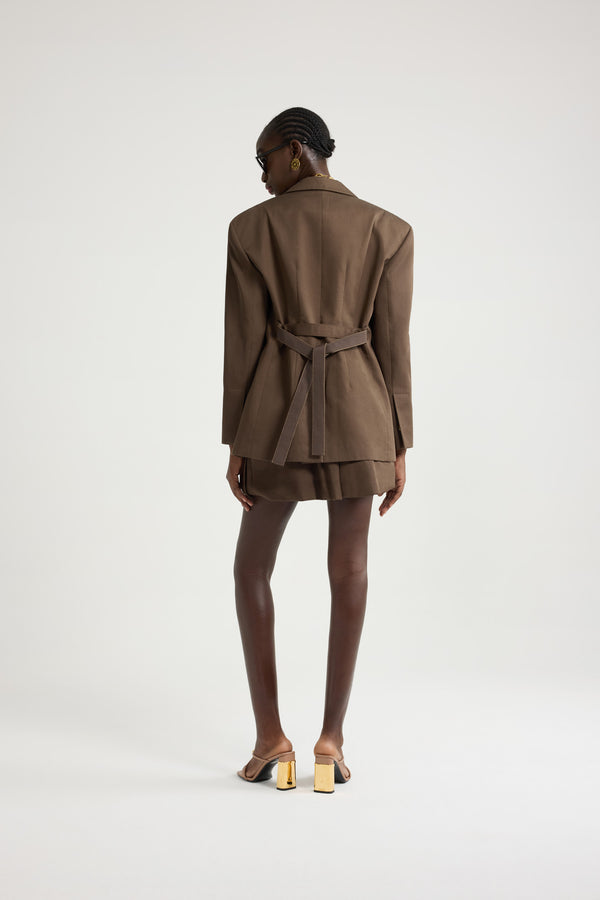 Patou - オーガニックコットンギャバジン オーバーサイズ ベルトジャケット - Java Brown - ジャバブラウンのオーガニックコットンギャバジン製ジャケット。オーバーサイズのテーラードシルエット。シングルブレストスタイル。ノッチラペル。パッド入りショルダー。ゴールドトーンのJP刻印入りボタン。チェストウェルトポケット、フラップポケット。ウエストに取り外し可能なセルフタイベルト左袖にJPモノグラム刺繍。裏地付き。