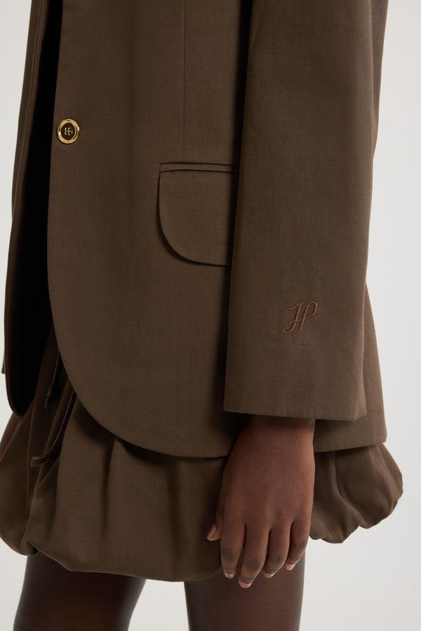 Patou - オーガニックコットンギャバジン オーバーサイズ ベルトジャケット - Java Brown - ジャバブラウンのオーガニックコットンギャバジン製ジャケット。オーバーサイズのテーラードシルエット。シングルブレストスタイル。ノッチラペル。パッド入りショルダー。ゴールドトーンのJP刻印入りボタン。チェストウェルトポケット、フラップポケット。ウエストに取り外し可能なセルフタイベルト左袖にJPモノグラム刺繍。裏地付き。