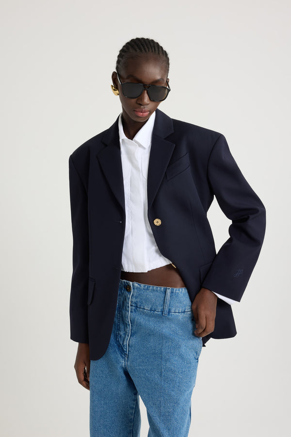 Patou - サステナブル テクニカル ウールツイル オーバーサイズ ベルテッドジャケット - Navy Black - ネイビーブラックのサステナブルなテクニカルウールツイルジャケット。オーバーサイズのテーラードシルエット。シングルブレストスタイル。ノッチラペル。パッド入りショルダー。ゴールドトーンのJP刻印入りボタン。チェストウェルトポケット、フラップポケット。ウエストに取り外し可能なセルフタイベルト左袖にJPモノグラム刺繍。裏地付き。