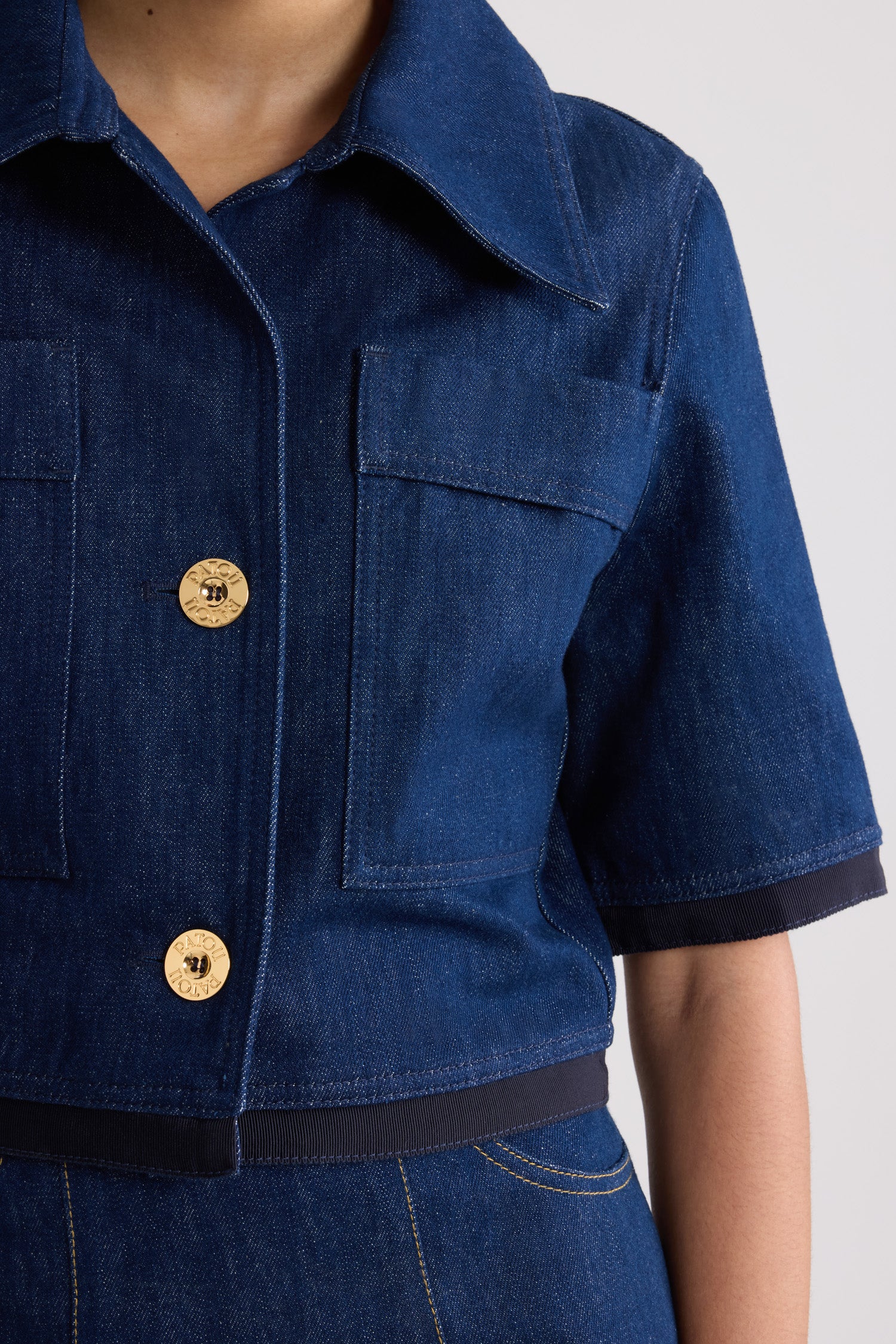 Patou - Short-sleeved cropped jacket in cotton denim - Rodeo Blue - Rodeo Blue cotton denim jacket. Cropped length. Wide collar. Gold-tone Patou logo-engraved buttons. Chest patch pockets. Elbow-length sleeves. Grosgrain trim at the cuffs and hem.