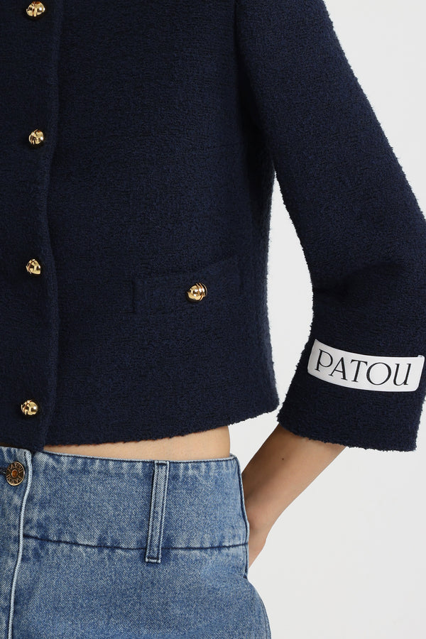 Patou - ライトウェイト オーガニックコットン ツイード ボクシー ノーカラージャケット - Navy Black - ネイビーブラックの薄手のオーガニックコットン製ツイードジャケット。ショート テーラード シルエット。シングルブレストスタイル。ゴールドトーンの半球型JPボタン。前面にボタン付きウェルトポケット。クロップドスリーブ。左袖にPatouロゴラベル。裏地付き。フィットスタイル。