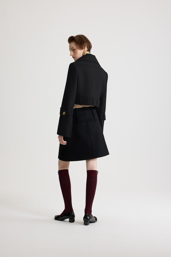 Patou - Belted cropped jacket in wool - Black - Black virgin wool jacket. Cropped silhouette. Single-breasted construction. Wide collar. Concealed button front fastening with silver-tone JP monogram-engraved buttons. Buttoned belt at the waist that can be worn open. Slightly flared sleeves with buttoned tabs. Patou logo label on the left sleeve. Lined.