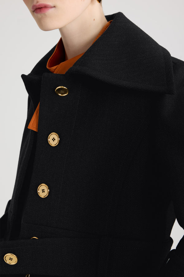 Patou - Belted cropped jacket in wool - Black - Black virgin wool jacket. Cropped silhouette. Single-breasted construction. Wide collar. Concealed button front fastening with silver-tone JP monogram-engraved buttons. Buttoned belt at the waist that can be worn open. Slightly flared sleeves with buttoned tabs. Patou logo label on the left sleeve. Lined.