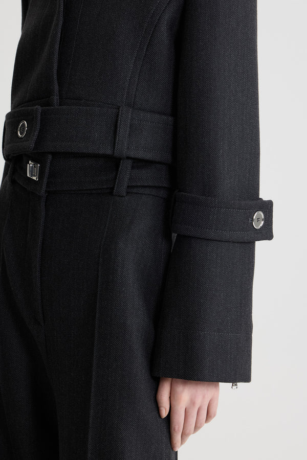 Patou - Veste courte ceinturée en laine - Mercury - Veste en laine vierge gris mercure. Silhouette courte. Construction à boutonnage simple. Col large. Boutonnage avant avec boutons argentés dissimulés gravés du monogramme JP. Ceinture boutonnée à la taille pouvant être portée ouverte. Manches légèrement évasées avec pattes boutonnées. Étiquette Patou sur la manche gauche. Modèle doublé.