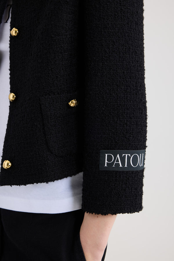Patou - Short collarless jacket in sustainable wool blend tweed - Black - Black sustainable wool blend tweed jacket. Short length. Single-breasted construction. Collarless design. Button front fastening with half-sphere gold-tone JP monogram buttons. Buttoned patch pockets at the front. Patou logo label on the left sleeve. Lined.