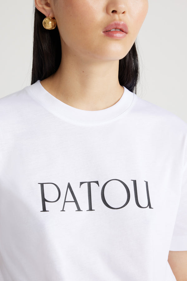 Patou - オーガニックコットン パトゥロゴTシャツ - White - ホワイトのオーガニックコットン製Tシャツ。クルーネック、レギュラーフィット。フロントにブラックのパトゥ レタリングロゴ。ユニセックスデザイン。 男性の方は、通常着用サイズのワンサイズ上をお選びください）。