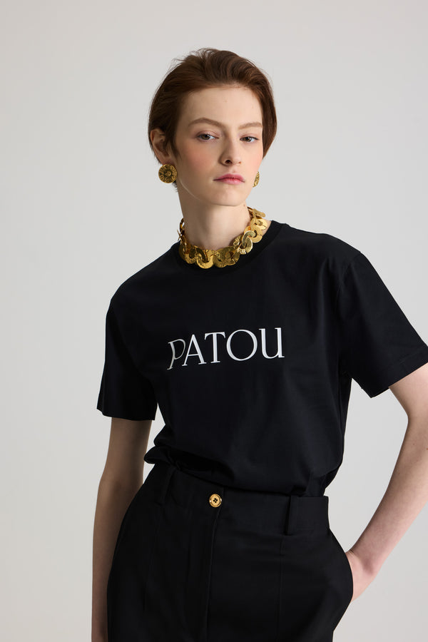 Patou - オーガニックコットン パトゥロゴTシャツ - Black - ブラックのオーガニックコットン製Tシャツ。クルーネック、レギュラーフィット。フロントにホワイトのパトゥ レタリングロゴ。ユニセックスデザイン。 男性の方は、通常着用サイズのワンサイズ上をお選びください）。