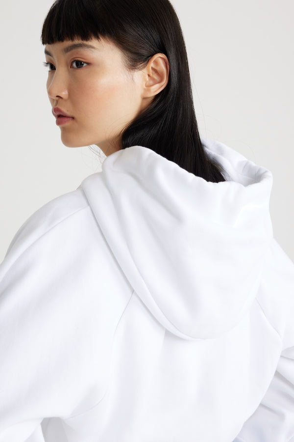 Patou - Medallion hoodie in organic cotton - White - White organic cotton sweatshirt. Relaxed silhouette. Hooded collar with grosgrain drawstring. Patou medallion logo embroidered at the front. Raglan sleeves. Ribbed cuffs and hem.This style is slightly cropped.