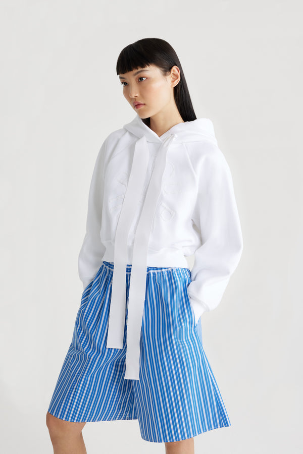 Patou - Medallion hoodie in organic cotton - White - White organic cotton sweatshirt. Relaxed silhouette. Hooded collar with grosgrain drawstring. Patou medallion logo embroidered at the front. Raglan sleeves. Ribbed cuffs and hem.This style is slightly cropped.