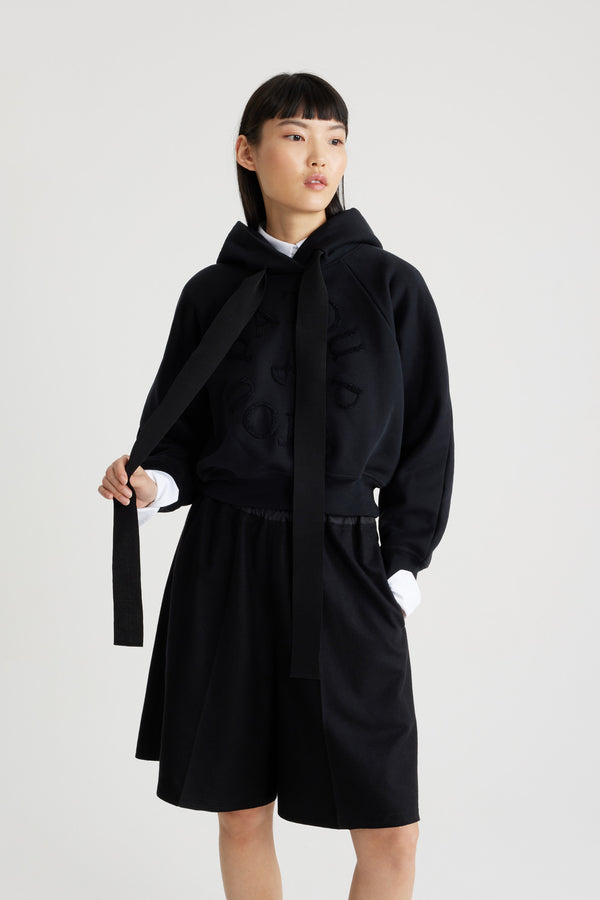 Patou - Felpa con logo medaglione in cotone bio - Black - Felpa in cotone bio nero. Vestibilità morbida. Collo con cappuccio e lacci in grosgrain. Logo Patou medaglione ricamato sul davanti. Maniche raglan. Polsini e orlo a costine.Questo modello è leggermente corto.