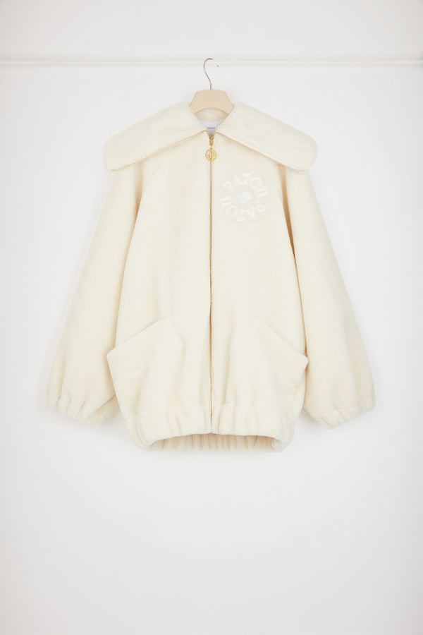 Patou - 재생 폴리에스터 소재의 인조 쉬어링 보머 재킷 - Avalanche - 순수한 쉬어링 감각.아발란체 화이트 재생 폴리에스터 보머 재킷. 인조 쉬어링 텍스처. 오버사이즈 실루엣. 과장된 디자인의 칼라. 시그니처 JP 풀탭이 달린 골드 톤 지퍼. 가슴의 파투 메달리온 로고 자수 장식. 앞면의 패치 포켓. 엘라스틱 커프스와 허리 부분.오버사이즈 스타일.