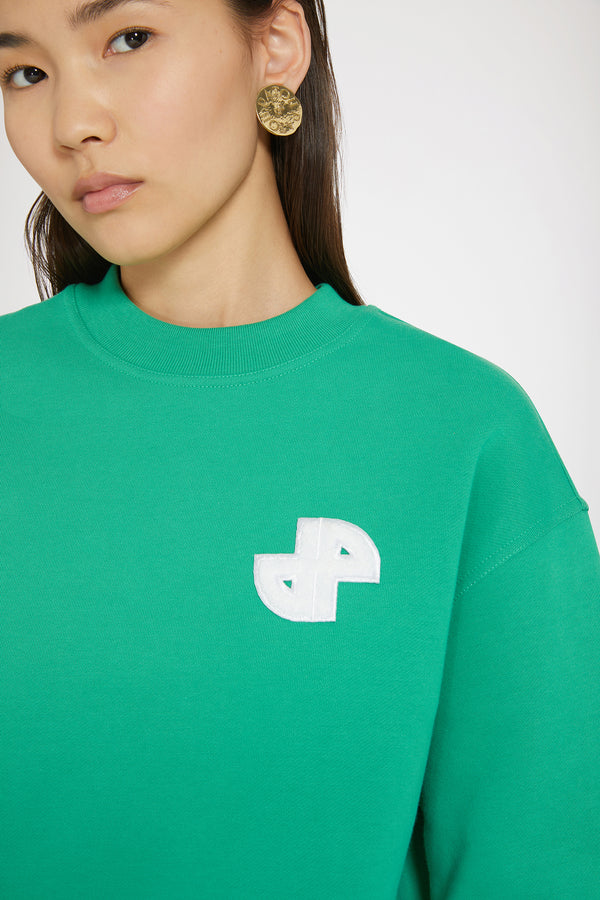 Patou - Sweatshirt JP en coton bio - Forest Green - Une signature minimaliste.Sweatshirt en coton bio vert forêt. Coupe classique. Col rond. Col, poignets et ourlet côtelés. Patch JP en bouclette à la poitrine.