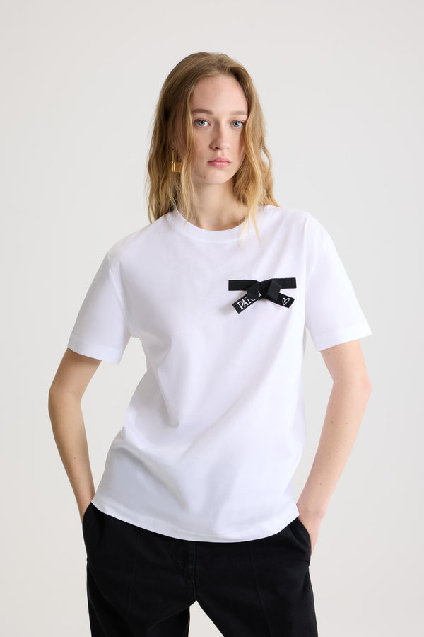 Patou - T-Shirt mit Schleife aus Bio-Baumwolle - Black - T-Shirt aus Bio-Baumwolle in Weiß. Normale Passform. Rundhalsausschnitt. Schleife aus Ripsband in Schwarz auf der Brust mit Patou Logo- und Herzstickerei.