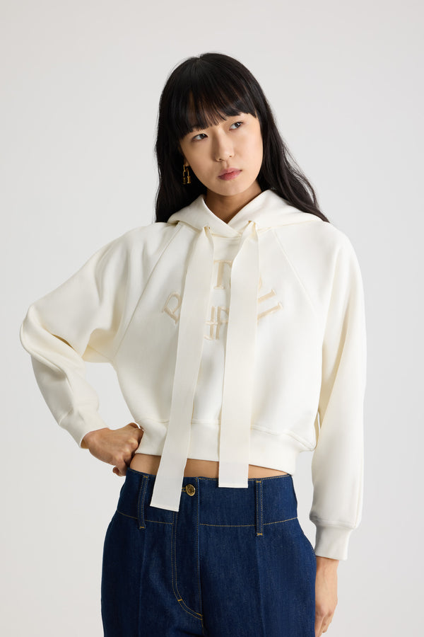 Patou - オーガニックコットン パトゥロゴ＆JPモノグラム フーディ - Snowberry White - スノーベリーホワイトのオーガニックコットン製スウェットシャツ。クロップド丈。フード付き襟にグログラン ドローストリング。前面にパトゥの刺しゅうロゴとJPモノグラム。ラグランスリーブ。リブ編みの袖口と裾。