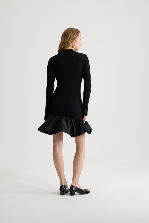 Patou - Ruffle hem ribbed mini dress in wool and faille - Black - Black Merino wool dress. Rib knit. Short length. Fitted silhouette. Mock neck. Gold-tone JP-engraved buttons on the shoulder. Elongated sleeves with split cuffs. Polyester faille ruffle hem.
