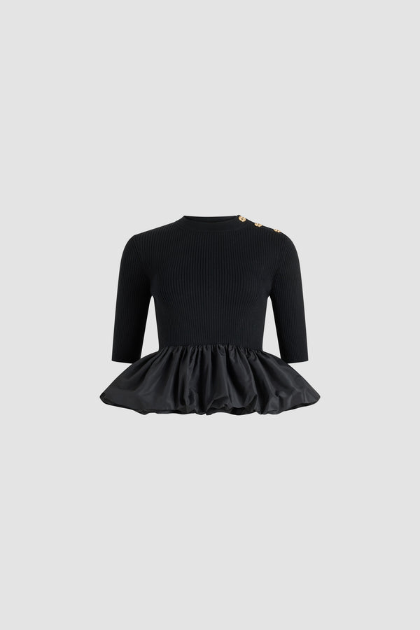 Patou - Ruffle hem ribbed jumper in wool and faille - Black - Black Merino wool jumper. Rib knit. Fitted silhouette. Mock neck. Gold-tone JP-engraved buttons on the shoulder. Mid-length sleeves. Polyester faille ruffle hem.
