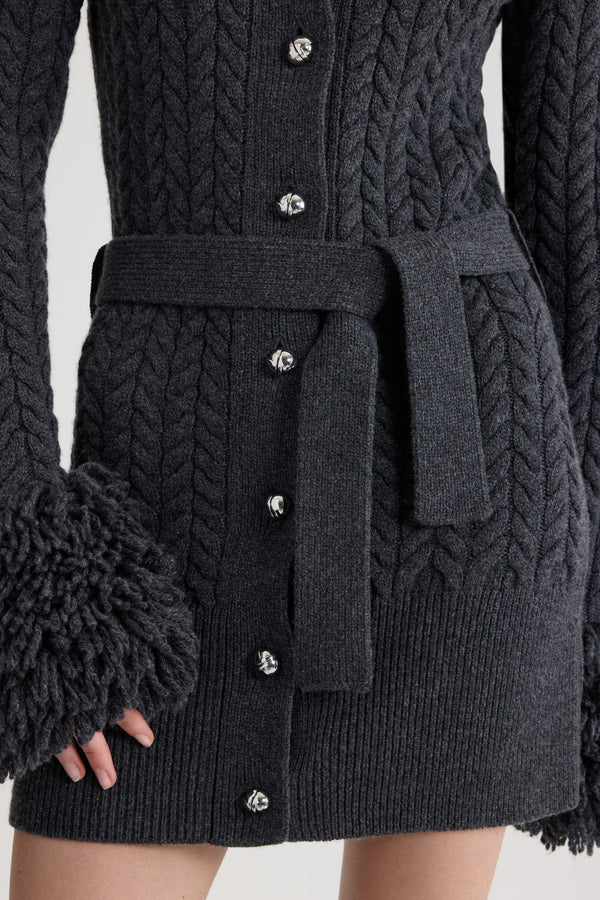 Patou - Lange Strickjacke mit Fransenverzierung aus Wolle und Kaschmir - Mercury - Cardigan aus Merinowolle und Kaschmir in Quecksilber-Grau. Zopfmuster-Strick. Lang geschnitten. Fransenverzierung in Felloptik an Halsausschnitt und Ärmelabschlüssen. Weiter Kragen. Knopfverschluss vorne mit silberfarbenen halbkugelförmigen JP-Knöpfen. Abnehmbarer Bindegürtel an der Taille. Gerippter Saum.