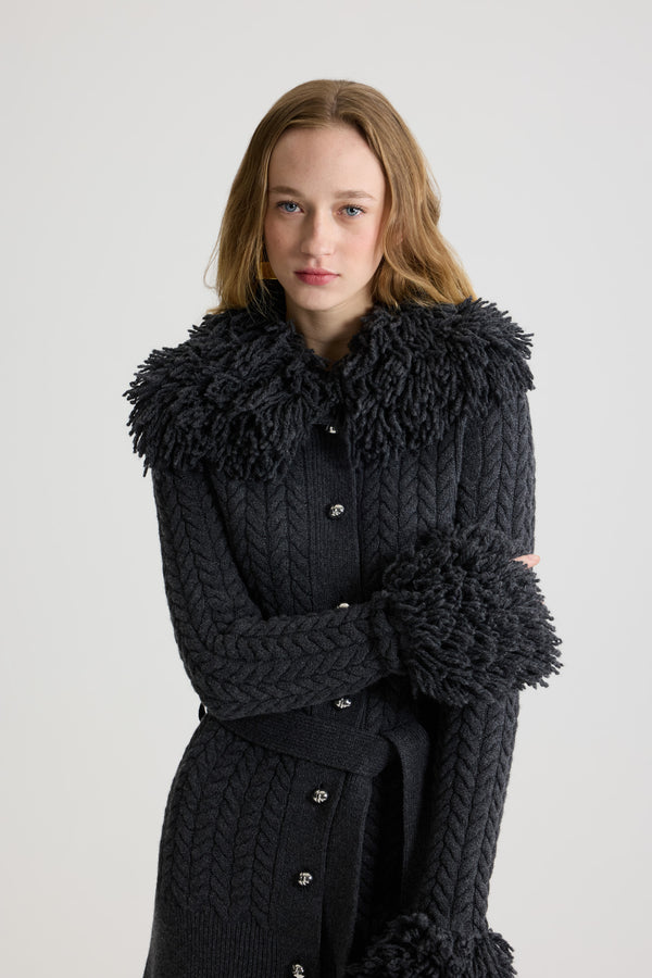 Patou - Lange Strickjacke mit Fransenverzierung aus Wolle und Kaschmir - Mercury - Cardigan aus Merinowolle und Kaschmir in Quecksilber-Grau. Zopfmuster-Strick. Lang geschnitten. Fransenverzierung in Felloptik an Halsausschnitt und Ärmelabschlüssen. Weiter Kragen. Knopfverschluss vorne mit silberfarbenen halbkugelförmigen JP-Knöpfen. Abnehmbarer Bindegürtel an der Taille. Gerippter Saum.