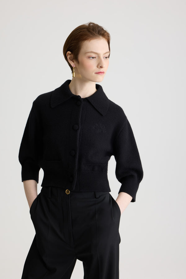 Patou - 울 소재 크롭 카디건 - Black - 블랙 컬러의 메리노 울 카디건. 크롭 길이. 셔츠 칼라. 패브릭으로 감싼 라운드 버튼 디테일의 앞면 버튼 클로저. 가슴 부분의 JP 모노그램 및 파투 로고 자수 장식. 미디 길이 벌룬 슬리브. 제트 포켓. 립 질감 커프스 및 헴.