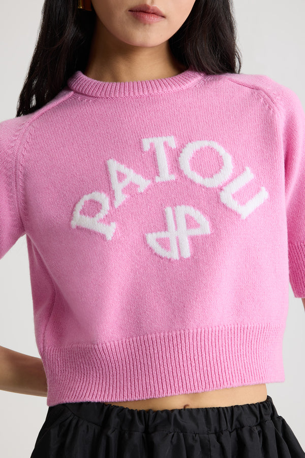 Patou - Pull court à logo Patou et monogramme JP en laine et cachemire - Pink Pearl - Pull en laine et cachemire rose perle. Modèle légèrement court. Col rond avec ruban en gros-grain à l’arrière. Logo Patou et JP contrastants en intarsia sur le devant. Manches courtes. Poignets et ourlet côtelés.