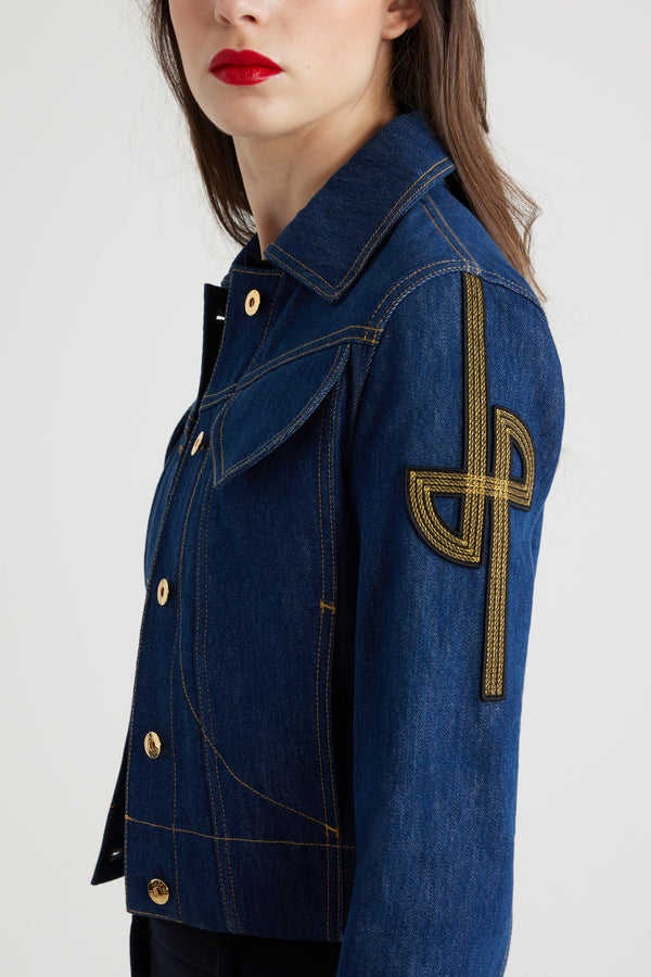 Patou - Giacca in denim con logo ricamato - Rodeo Blue - Giacca corta in denim bio blu scuro con cuciture a contrasto. Logo JP stilizzato ricamato sulla manica sinistra. Chiusura con bottoni dorati incisi JP. Due tasche con pattina sul petto, due tasche laterali. Cinturini in vita e ai polsi.Fitted jacket (select one size up for a loose look).