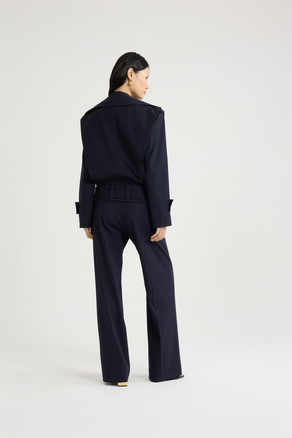 Patou - サステナブル テクニカル ウールツイル ベルテッドジャケット - Navy Black - ネイビーブラックのサステナブルなテクニカルウールツイルジャケット。ルーズフィット。ワイドカラー。ボタン付きのショルダー＆カフスタブ。前面にボタン開閉。ゴールドトーンのパトゥロゴ刻印入りボタン。ウエストに幅広の布製ベルト。サイドにポケット。トップステッチ ディテール。裏地付き。
