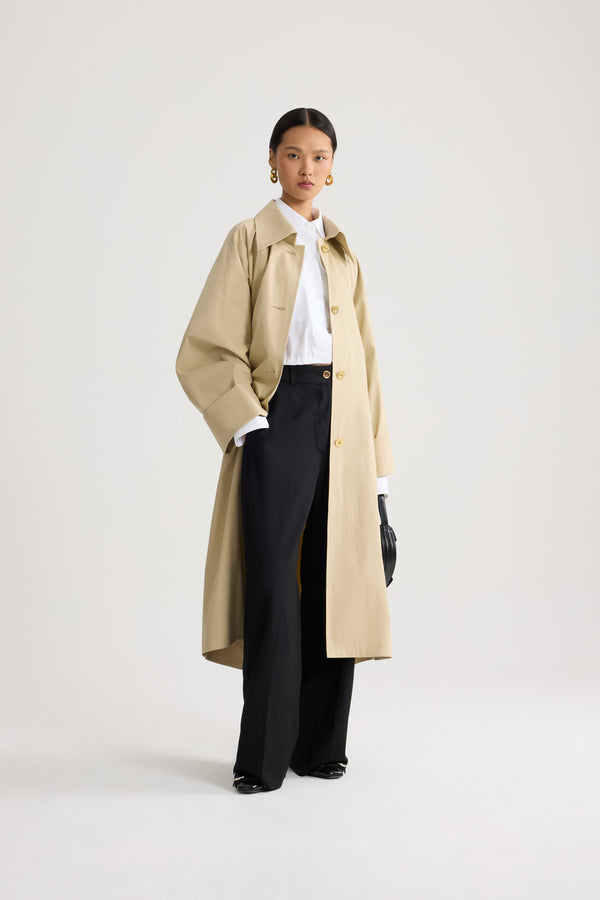 Patou - Trench-coat léger en coton bio - Safari Sand - Trench-coat léger couleur sable. Ceinture amovible à la taille. Double boutonnage doré.