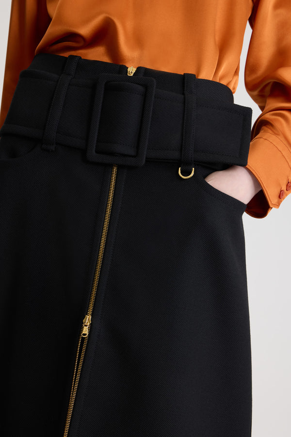 Patou - Jupe midi ceinturée zippée à l’avant en laine - Black - Jupe en laine vierge noire. Longueur midi. Taille basse. Fermeture par zip doré à double curseur à l’avant. Ceinture large en tissu sur les hanches avec boucle recouverte de tissu et anneau doré. Poches basses sur le devant.