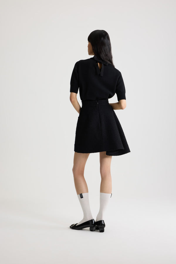 Patou - Asymmetric mini skirt in sustainable wool blend tweed - Black - Black sustainable wool blend tweed skirt. Short length. Mid waist. Asymmetric silhouette with pleating on one side. Zip fastening at the back. Single rounded pocket at the side. Lined.